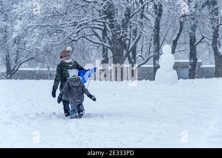 Montreal, QC, Canada - 16 Gennaio 2021: Madre e bambino camminano nel parco Jeanne-Mance durante la tempesta di neve. Foto Stock