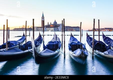 Gondola veneziana all'alba, gondole ormeggiate a Venezia con il Monastero di San Giorgio sullo sfondo, Italia Foto Stock