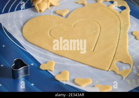 Cucina casereccia torta a forma di cuore. Arrotolare l'impasto sul tavolo e tagliarlo con l'aiuto di stampi. Istruzioni dettagliate Foto Stock