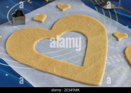 Cucina casereccia torta a forma di cuore. Arrotolare l'impasto sulla pergamena e tagliarlo con l'ausilio di stampi. Istruzioni dettagliate Foto Stock