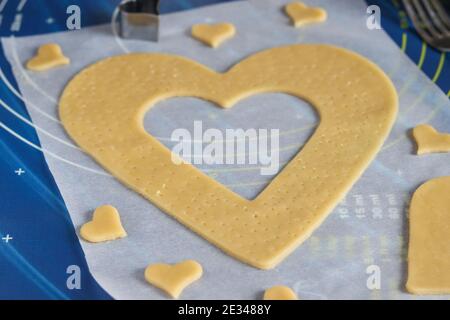 Cucina casereccia torta a forma di cuore. Arrotolare l'impasto sulla pergamena e tagliarlo con l'ausilio di stampi. Istruzioni dettagliate Foto Stock