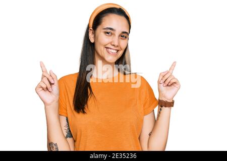 Giovane donna ispanica che indossa abiti casual sorridente sicuro puntando con le dita a diverse direzioni. Copy spazio per la pubblicità Foto Stock