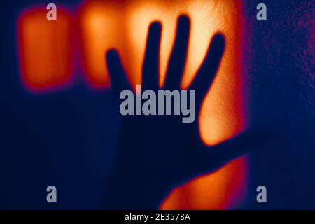 Ombra della mano sul muro . Dita nella luce debole Foto Stock