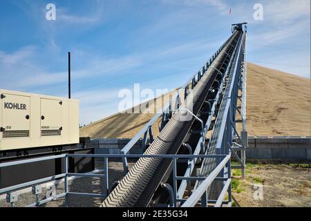 Nastro trasportatore su cumulo di grano raccolto immagazzinato fuori nello stato orientale di Washington in attesa di esportazione in Asia Sky Foto Stock