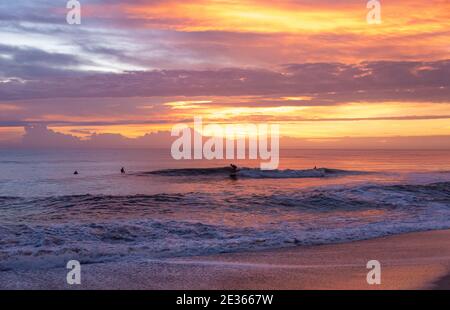 I surfisti della Florida salutano la giornata con una sessione di surf in pattuglia all'alba bagnata dal vivace colore dell'alba al Mickler's Landing a Ponte Vedra Beach, Florida. Foto Stock