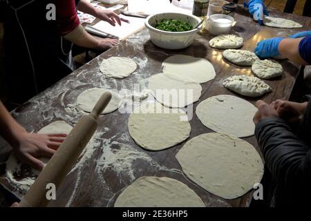 I rifugiati che fuggirono dalla regione del Nagorno-Karabakh rendono i cappelli jingalov tradizionali Pani farciti di erbe nella capitale centrale di Yerevan dell'Armenia Foto Stock