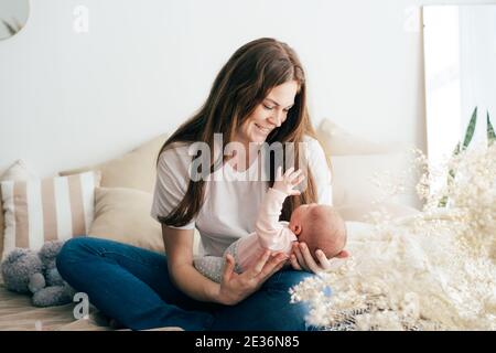 La giovane adorabile madre bianca dai capelli rossi si prende cura con amore del suo neonato per il piacere. Foto Stock