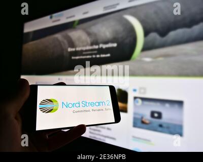 Persona in possesso di smartphone con logo del progetto di gasdotto offshore Nord Stream 2 nel Mare del Nord. Mettere a fuoco sulla parte sinistra dello schermo del telefono cellulare. Foto Stock