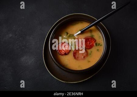 Zuppa di Caldo Verde con verdure e chorizo tritato sulla parte superiore della ciotola su sfondo scuro. Foto Stock