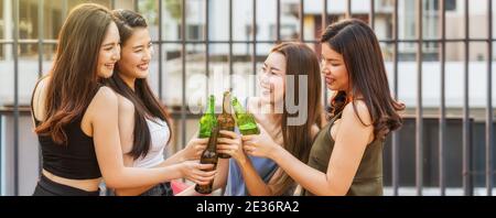 Felicità Asian Girl Friend Group festeggiando e salutando insieme con la sua bottiglia di birra al tramonto sul tetto del centro hotel o nightclub, galline Foto Stock