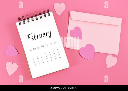 Piatto Lay con foglio di calendario di febbraio con San Valentino in su il 14 circondato da cuori e lettera d'amore su rosa sfondo Foto Stock