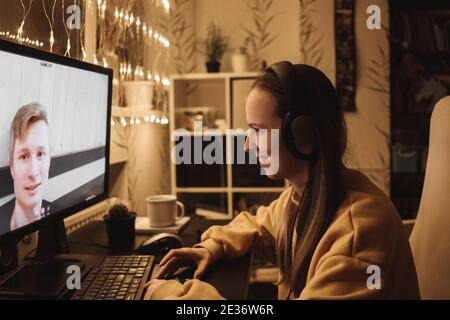 Donna che fa una videochiamata all'uomo usando il computer, guardando lo schermo con la web chat virtuale, primo piano. La moglie e il marito parlano di festa. Garland sullo sfondo Foto Stock