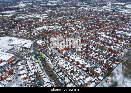 Foto aerea di una giornata innevata nella città di Leeds nel Regno Unito, che mostra file di case con terrazze con tetti innevati nel villaggio di Beeston nel wi Foto Stock