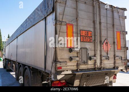 Carrello per il trasporto di merci sfuse con pannelli ed etichette di pericolo a causa del carico di solidi infiammabili spontanei. Foto Stock