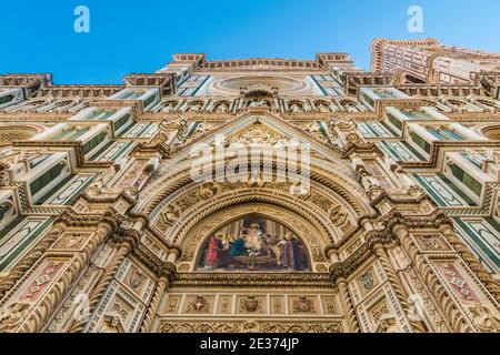 Impressionante vista a basso angolo della facciata principale del Duomo di Firenze; dalla lunetta del portale centrale con un colorato mosaico di Cristo intronizzato,... Foto Stock