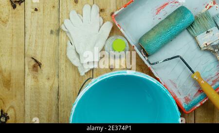 Set di attrezzi per la verniciatura di pareti su sfondo di legno a casa. Foto Stock