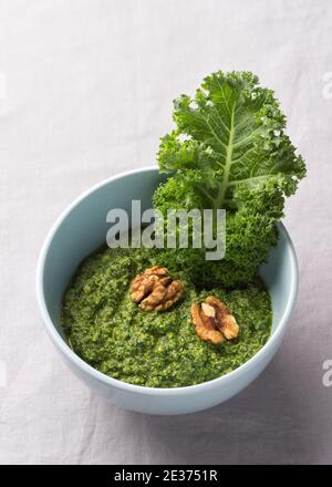 Pesto verde di kale, noci, aglio e olio d'oliva su sfondo grigio. Cibo sano e delizioso Foto Stock