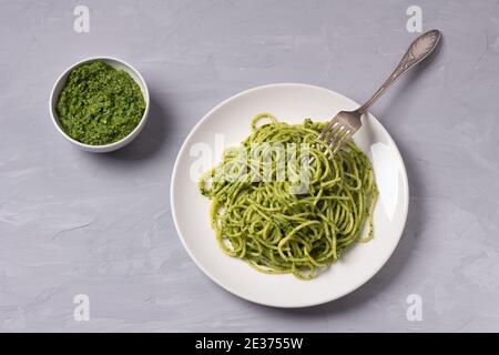 Spaghetti con pesto verde di kale, noci, aglio e olio d'oliva su sfondo grigio. Vista dall'alto. Deliziosi piatti fatti in casa Foto Stock