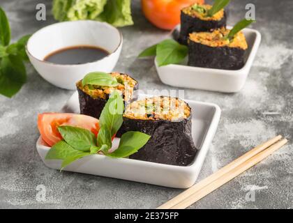 Involtini crudi con ripieno di verdure avvolte in alghe con basilico erbe e salsa di soia su sfondo grigio Foto Stock