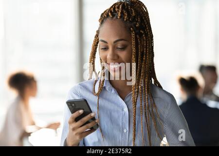 Sorridente donna etnica utilizzare smartphone SMS on-line Foto Stock