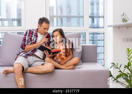 Padre che legge la Bibbia alla sua bambina figlia a casa Foto Stock