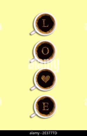 Quattro tazze con caffè espresso con schiuma e l'iscrizione amore su sfondo giallo in verticale. Biglietto d'auguri per San Valentino, cuore Foto Stock