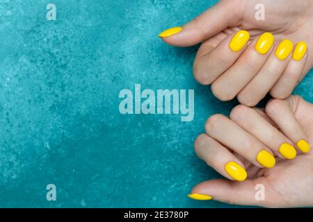 Manicure con trendy colore giallo di smalto sulle mani femminili. Design minimo. Posiziona per il testo, spazio per la copia. Mockup di bellezza, concetto di cosmetologia. Casu Foto Stock