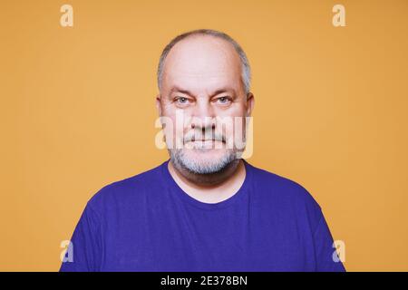 ritratto dell'uomo anziano con i capelli bianchi grigi e. barba sullo sfondo dello studio di colore arancione Foto Stock