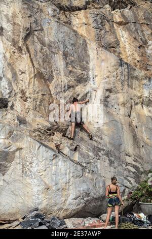 Cima corda arrampicata rocce o top ropping, sistema di ancoraggio in cima alla salita e giù a un credente ai piedi della salita. Foto Stock