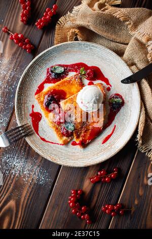 Frittelle con gelato e frutti di bosco su fondo di legno. Foto Stock