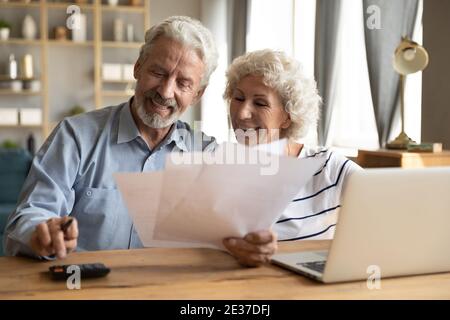 Felice coppia di famiglia più anziana matura calcolando le spese domestiche. Foto Stock