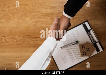 Concetto di bene immobile, sigilla un affare. Vista dall'alto dell'agente bancario che sta scuotendo le mani con il giovane uomo per il successo dell'affare. Casa affitto acquistare vendere concetto Foto Stock