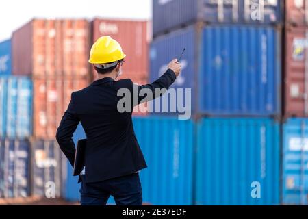 il lavoratore di caposquadra usa un porto di carico del contenitore di controllo radio a lunga distanza per caricare i contenitori. Logistica importazione esportazione spedizione concetto. Foto Stock