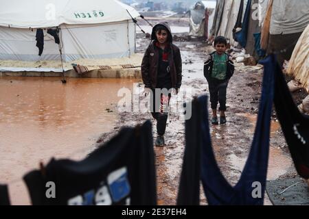 Kafr Aruq, Siria. 17 gennaio 2021. I bambini siriani camminano attraverso il campo allagato di tal Amin per gli sfollati interni, vicino al villaggio di Kafr Aruq. I campi profughi nel nord del governatorato dell'Idlib sono stati minacciati da condizioni climatiche estreme in quanto sono stati allagati a seguito di forti piogge nei giorni precedenti. Credit: ANAS Alkharboutli/dpa/Alamy Live News Foto Stock