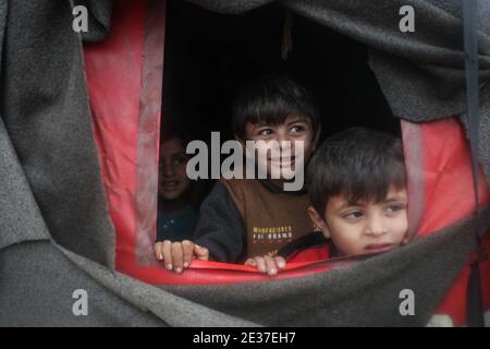 Kafr Aruq, Siria. 17 gennaio 2021. I bambini siriani sbirciano fuori da una tenda nel campo allagato di tal Amin per gli sfollati interni, vicino al villaggio di Kafr Aruq. I campi profughi nel nord del governatorato dell'Idlib sono stati minacciati da condizioni climatiche estreme in quanto sono stati allagati a seguito di forti piogge nei giorni precedenti. Credit: ANAS Alkharboutli/dpa/Alamy Live News Foto Stock