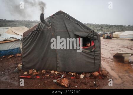 Kafr Aruq, Siria. 17 gennaio 2021. I bambini siriani sbirciano fuori da una tenda nel campo allagato di tal Amin per gli sfollati interni, vicino al villaggio di Kafr Aruq. I campi profughi nel nord del governatorato dell'Idlib sono stati minacciati da condizioni climatiche estreme in quanto sono stati allagati a seguito di forti piogge nei giorni precedenti. Credit: ANAS Alkharboutli/dpa/Alamy Live News Foto Stock