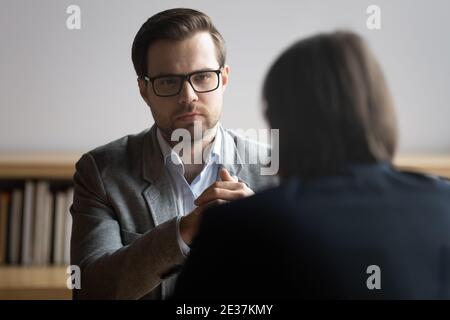 Responsabile ore maschile concentrato in occhiali ascoltando il candidato di lavoro. Foto Stock