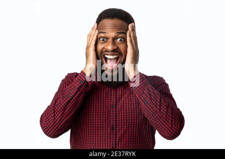 L'uomo afro-americano eccitato gridando testa toccante su sfondo bianco Foto Stock
