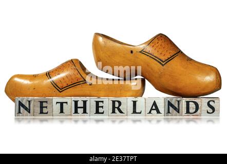 Primo piano di un paio di zoccoli olandesi in legno e il testo olandese, in blocchi di legno, isolati su sfondo bianco con riflessi. Foto Stock