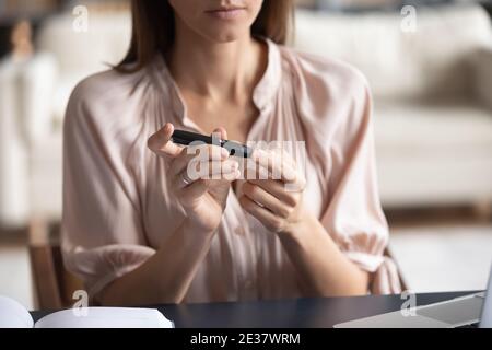 Primo piano donna che misura il livello di glucosio, usando la penna di lancet Foto Stock