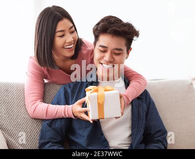 Moglie asiatica che dà il regalo al marito su San Valentino a casa Foto Stock
