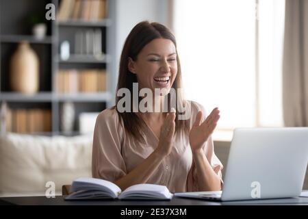 Donna molto contentita che guarda lo schermo del notebook, sorpresa da buone notizie Foto Stock