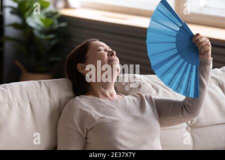 Primo piano esaurita donna di mezza età che agita la ventola della carta Foto Stock