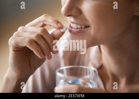Primo piano donna sorridente che tiene la pillola e un bicchiere d'acqua Foto Stock