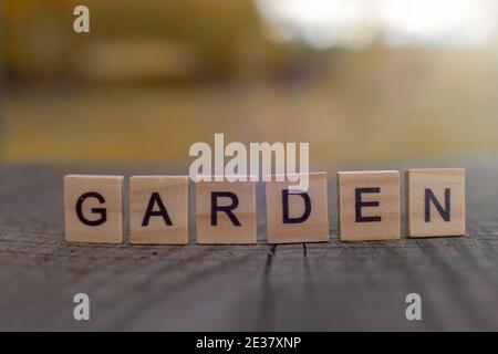 Lettera in legno nella parola Giardino, si erge di un tavolo grigio in legno con vista sul paesaggio autunnale Foto Stock