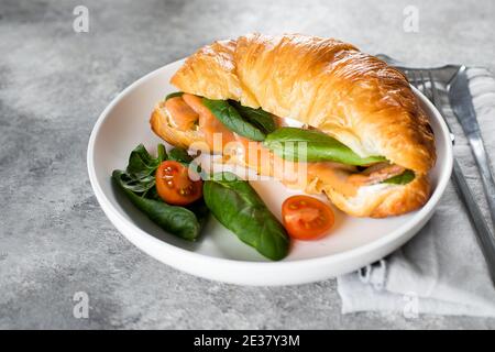 Panino di croissant con formaggio di cottage, salmone, spinaci. Colazione sana Foto Stock