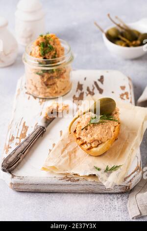 Insaporire con deliziosi pate di pollo fatti in casa con spezie e aneto in un vaso di vetro e una fetta di pane nelle vicinanze e cappero su uno sfondo chiaro. S Foto Stock