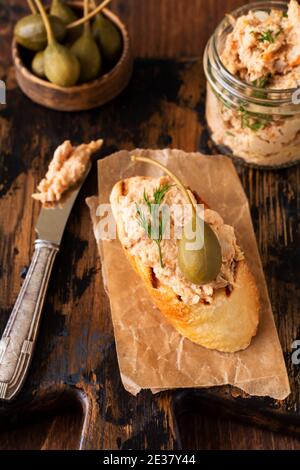 Sandwich con delizioso pate di pollo fatto in casa con spezie e aneto in un vaso di vetro e una fetta di pane nelle vicinanze e cappero servito in stile vintage su vecchio Foto Stock