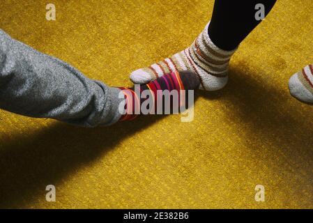 piedi di donna e uomo con calze colorate su tappeto giallo. amore in casa Foto Stock