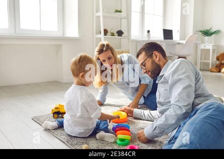 Mamma, papà e bambino che giocano a casa con una seduta colorata sul pavimento nel soggiorno. Foto Stock